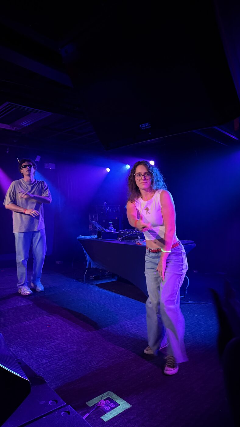 Two people dancing at a club under purple lights